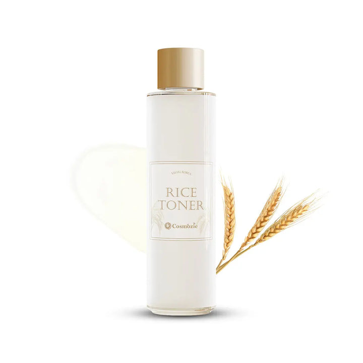 White bottle of rice toner with a gold cap and wheat stalks on a white background